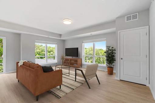 A living room with a brown couch, a chair, a television, and a potted plant.