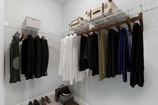 A white closet with clothes hanging and shoes on the floor.