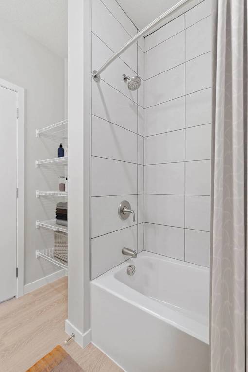 A white bathroom with a white tub and a white shower curtain.