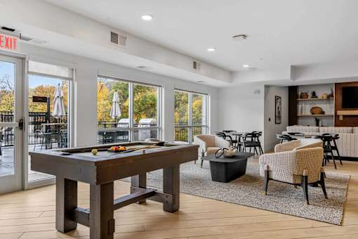 A billiard table is in the middle of a room with a pool table and a bar in the background.