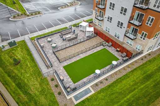 A small grassy area surrounded by a fence and a building.