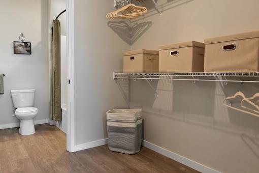 A white toilet is in a small bathroom with a shelf above it.