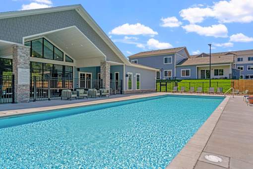 A swimming pool in front of a building with a white roof.