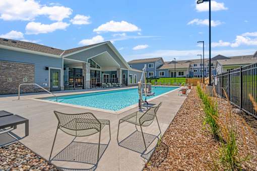 A pool area with chairs and a building in the background.