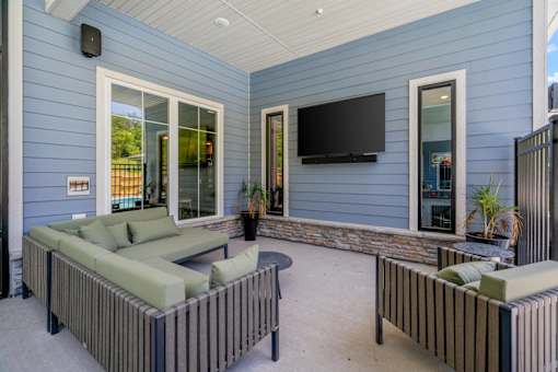 A patio with a couch, a table, and a television.