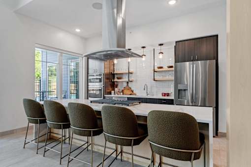 A modern kitchen with a large island and chairs.