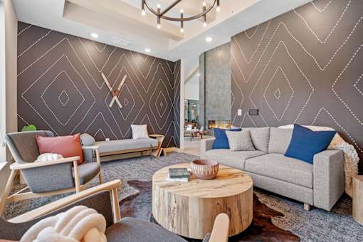 A living room with a grey sofa, a wooden coffee table, and a large wall clock.