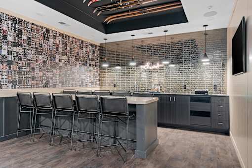 A bar area with a row of chairs and a television on the wall.
