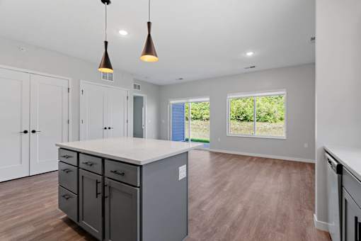 A kitchen with a large island and pendant lights.