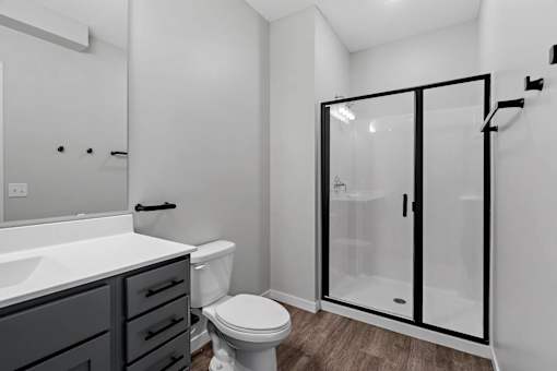 A white bathroom with a toilet, sink, and shower.