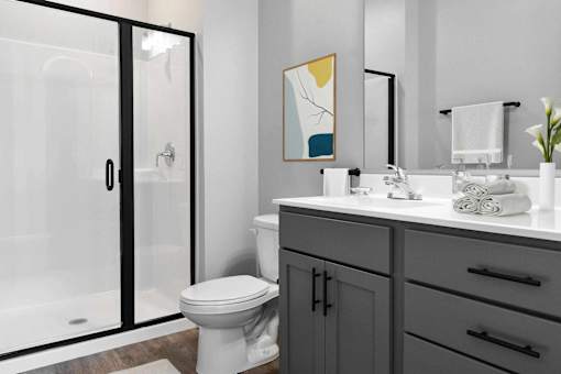 A bathroom with a toilet, sink, and a glass shower door.