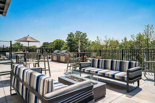 A patio with striped couches and a table with a fire pit.