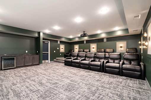 A home theater with a row of black leather seats and a ceiling fan.