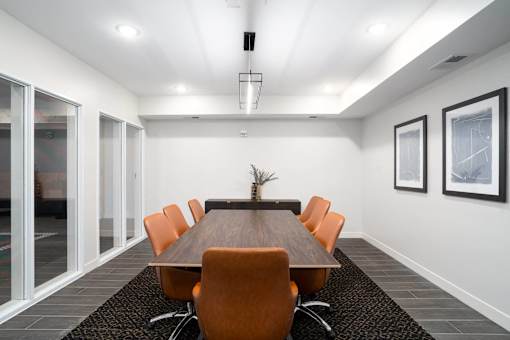 A conference room with a long table and orange chairs.