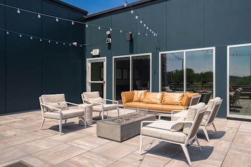 A patio with a couch, chairs, and a fire pit.