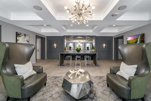 A modern living room with two green leather chairs and a coffee table in the center.