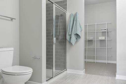 A bathroom with a toilet, a glass shower door, and a towel hanging on the door.