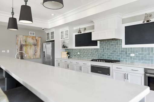 A kitchen with white cabinets and a white island.