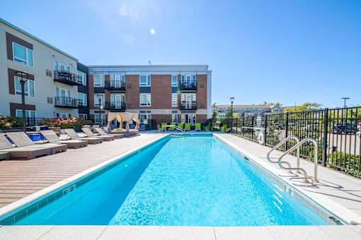 A large swimming pool in front of a multi-story apartment building.