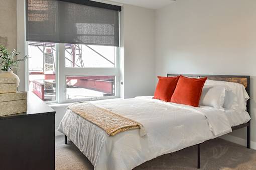 A bedroom with a large bed and a window overlooking a construction site.