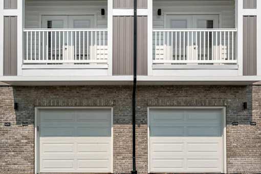 A building with two garage doors and a balcony.
