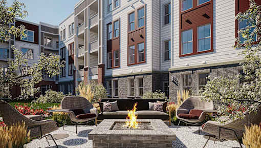 A fire pit sits in the middle of a patio surrounded by chairs and plants.