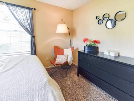 A bedroom with a bed, chair, and dresser.