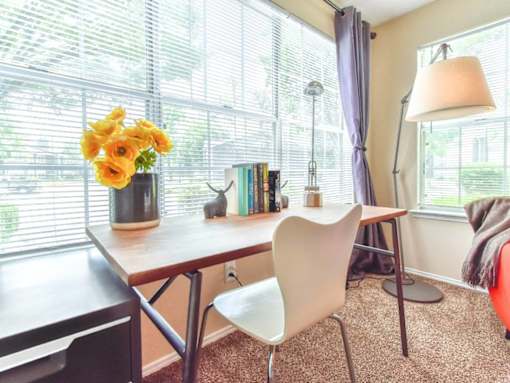 A room with a table, chairs, and a vase of flowers.