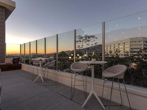 A balcony with a table and chairs overlooking a cityscape at dusk.