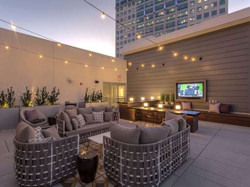 A patio with a couch, chairs, and a television on the wall.