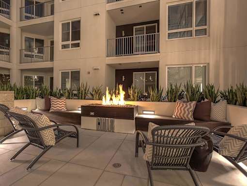 A patio with chairs and a fire pit in front of a building.
