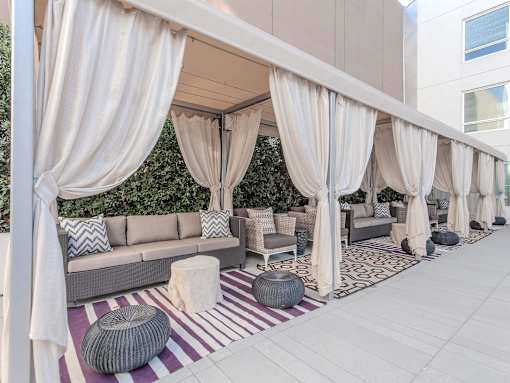 A patio with a white canopy and grey furniture.