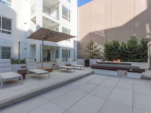 A patio with a fire pit and lounge chairs.