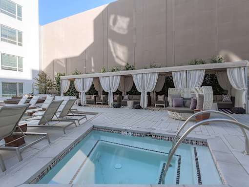 A pool area with a hot tub and lounge chairs.