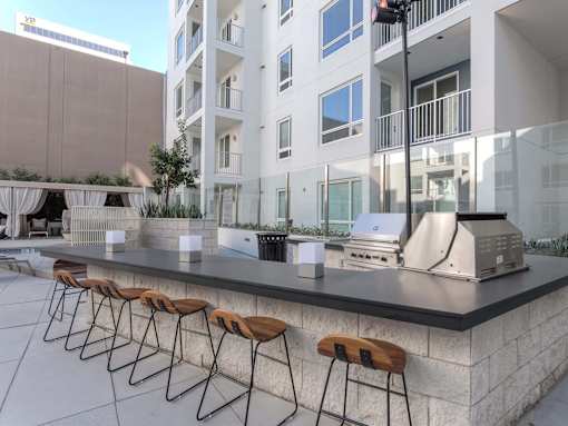 A bar with stools is in front of a building.