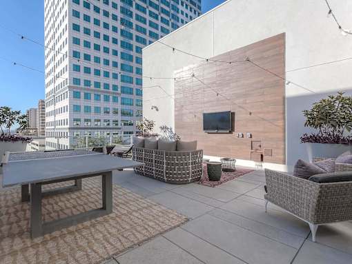 A patio with a table, chairs, and a television on a wall.