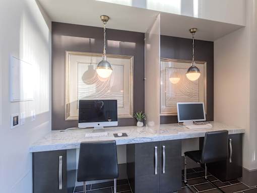 A modern home office with a marble desk and two chairs.