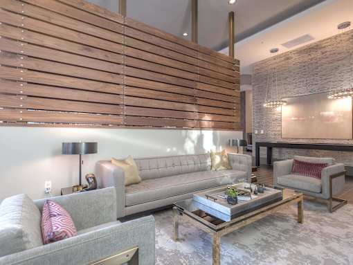 A modern living room with a grey couch, a coffee table, and a wooden slat wall.