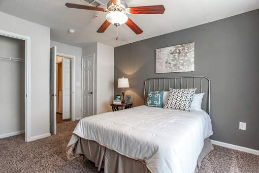 A bedroom with a white bed and a ceiling fan.