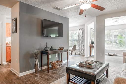 A living room with a grey wall and a flat screen TV mounted on it.