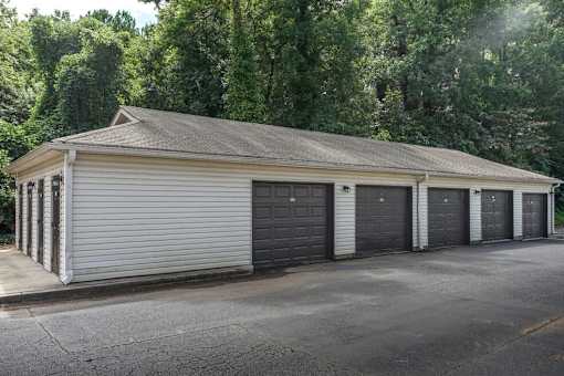 A two-story garage with four doors is surrounded by trees.