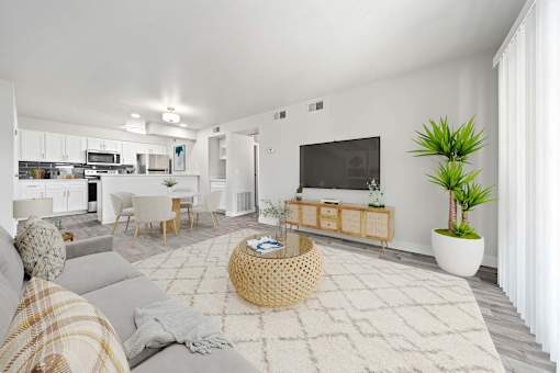 A modern living room with a grey sofa, a woven coffee table, and a flat-screen TV.