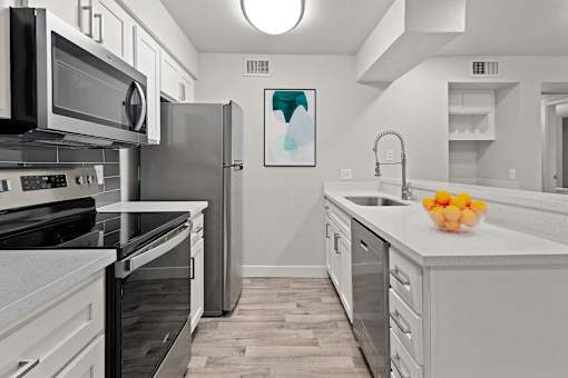 A kitchen with white cabinets and a black microwave.
