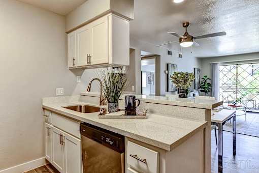 A kitchen with white cabinets and a marble countertop.