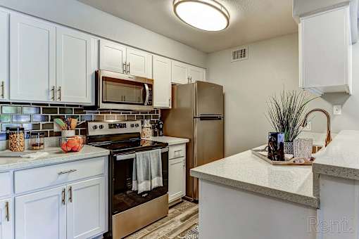 A kitchen with white cabinets and a stainless steel refrigerator.