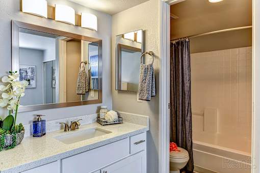 A bathroom with a sink, mirror, and shower.