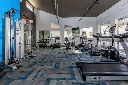 A gym with a variety of equipment including treadmills, weights, and exercise machines.
