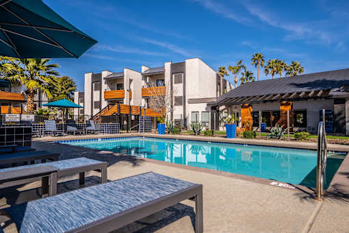A pool area with a bench and a table in front of a building.