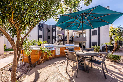 A patio with a table and chairs under a blue umbrella.