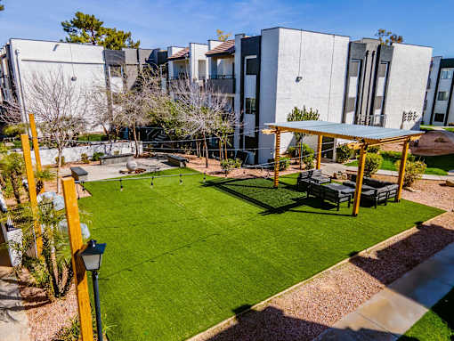 A sunny day at a modern building with a green lawn and a pavilion.